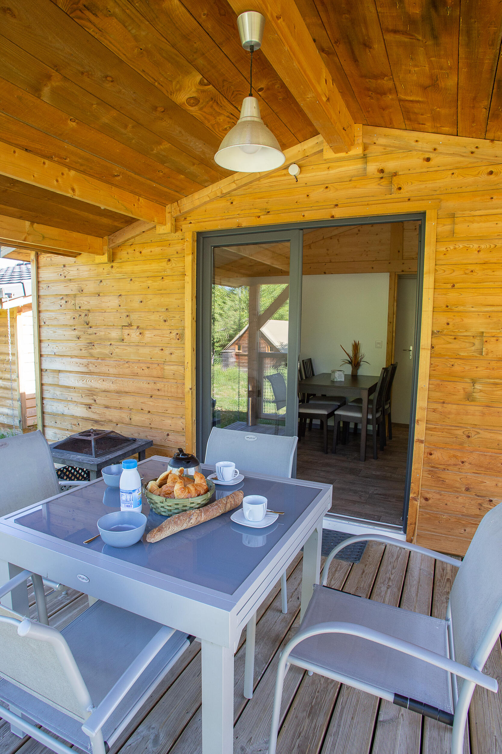 Petit déjeuner sur la terrasse en bois d'un chalet Libella au camping familial Détente et Clapotis, Lac de Paladru